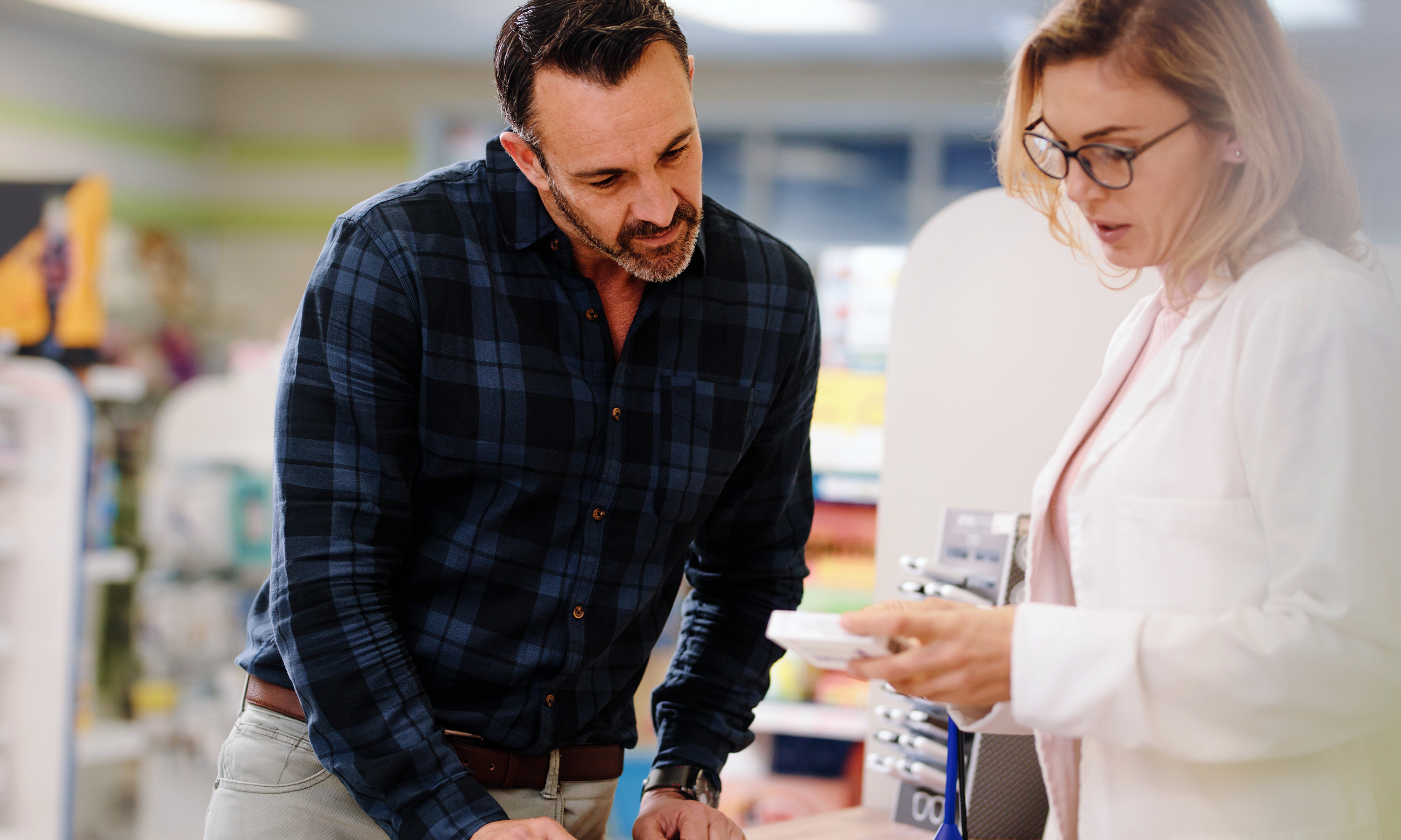 Stock picture of a community pharmacist giving advice on medication to a customer 