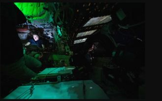 NASA astronaut Christina Koch reads on a tablet in the dimly lit Orion spacecraf