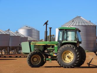 Carnaby’s cockatoo sitting on top of tractor near a grain silo in the Wheatbelt.