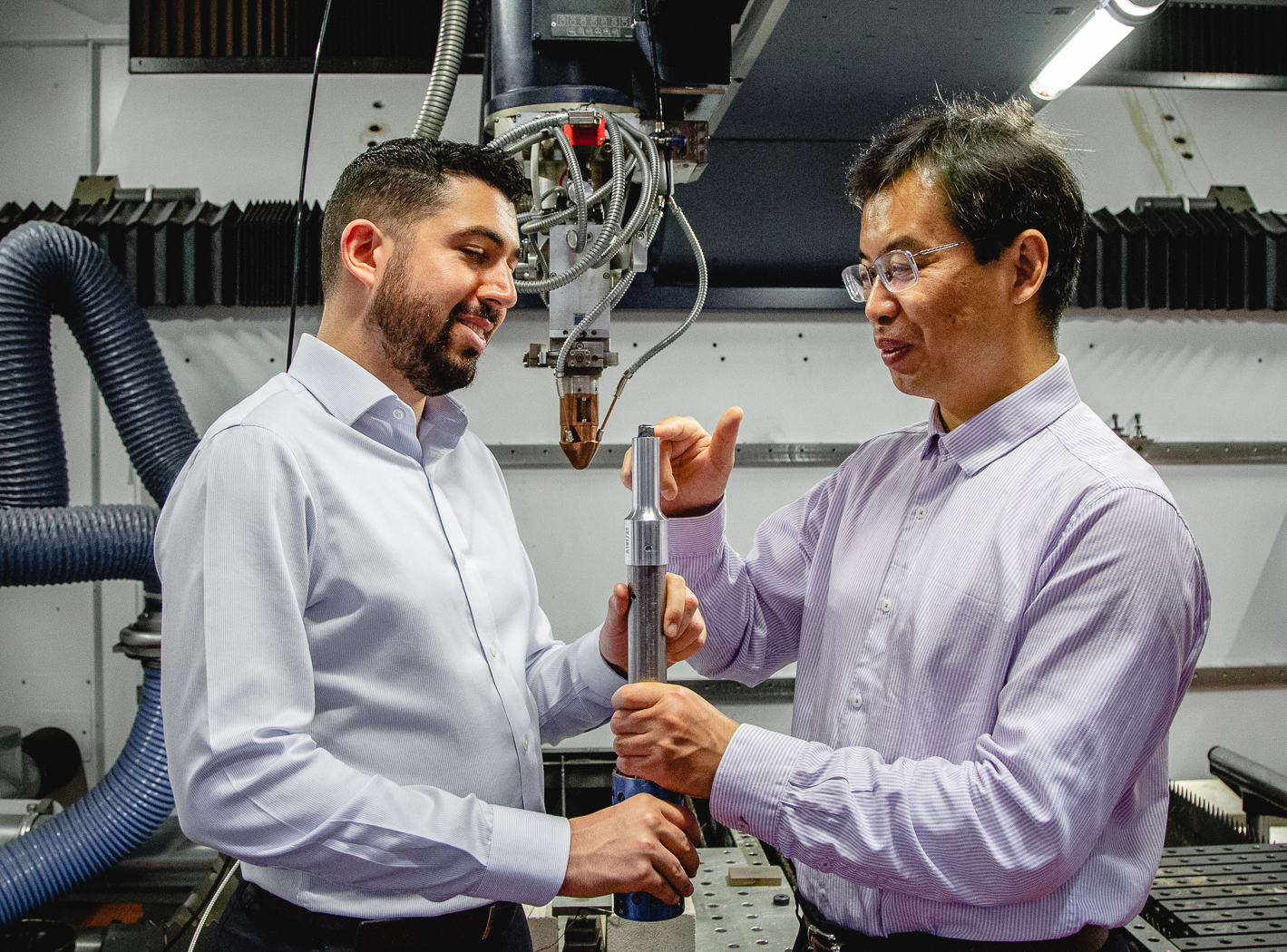 Carmelo Todaro and Ma Qian inspect a 3D printed Titanium alloy cube on the tip of an ultrasound rod. Credit: RMIT University