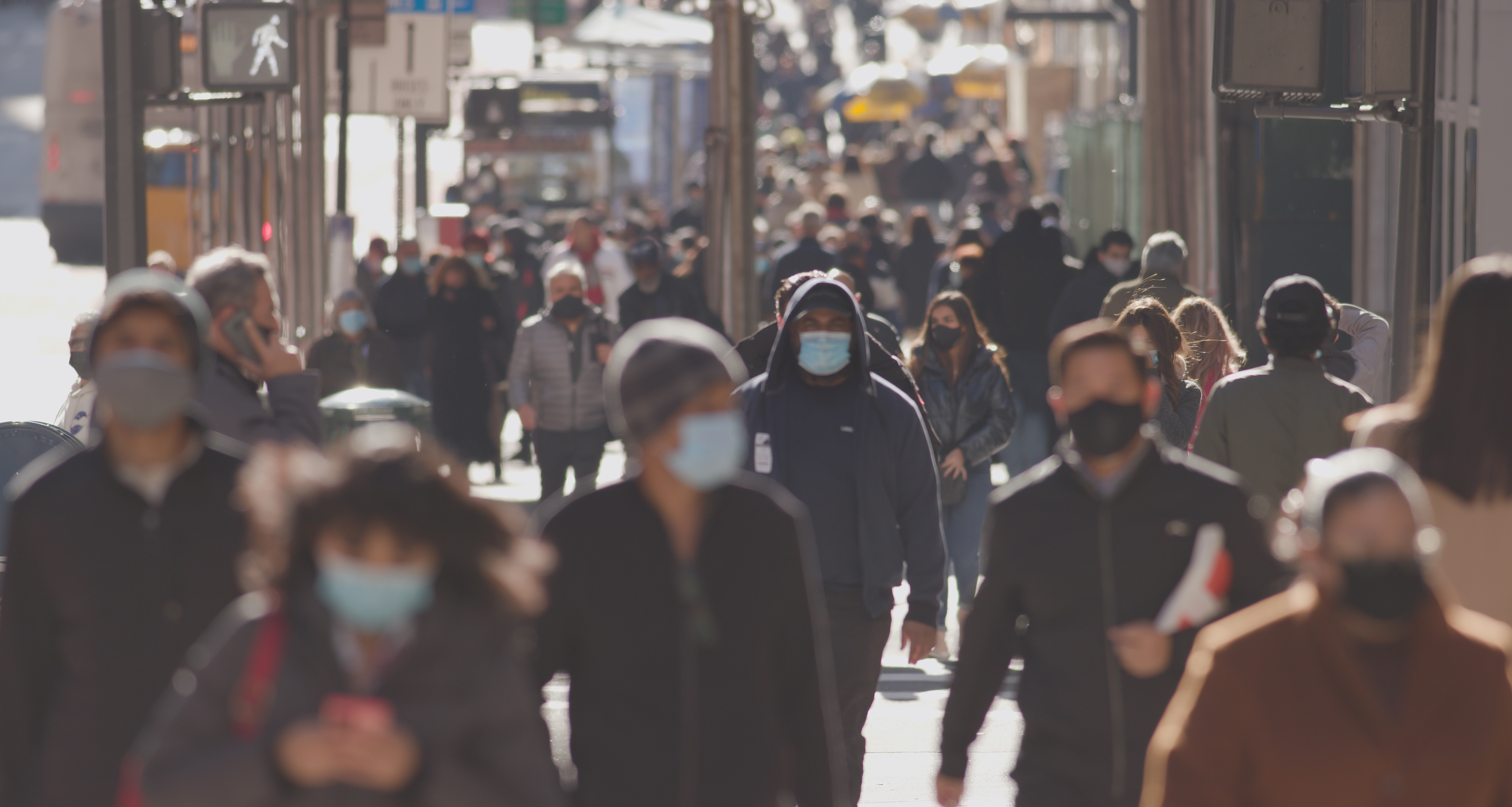 Anonymous crowd of people walking street wearing masks during covid 19 coronavirus pandemic. By blvdone