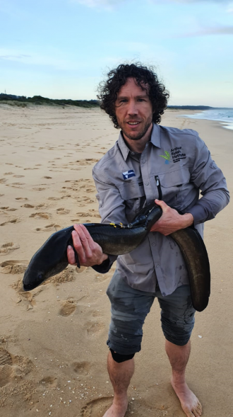 Dr Wayne Koster holding tagged eel