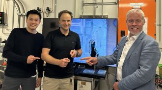 Research team holding the chip in front of an enlarged detail of the chip