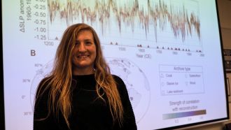 Headshot of Dr Georgy Falster in front of graph