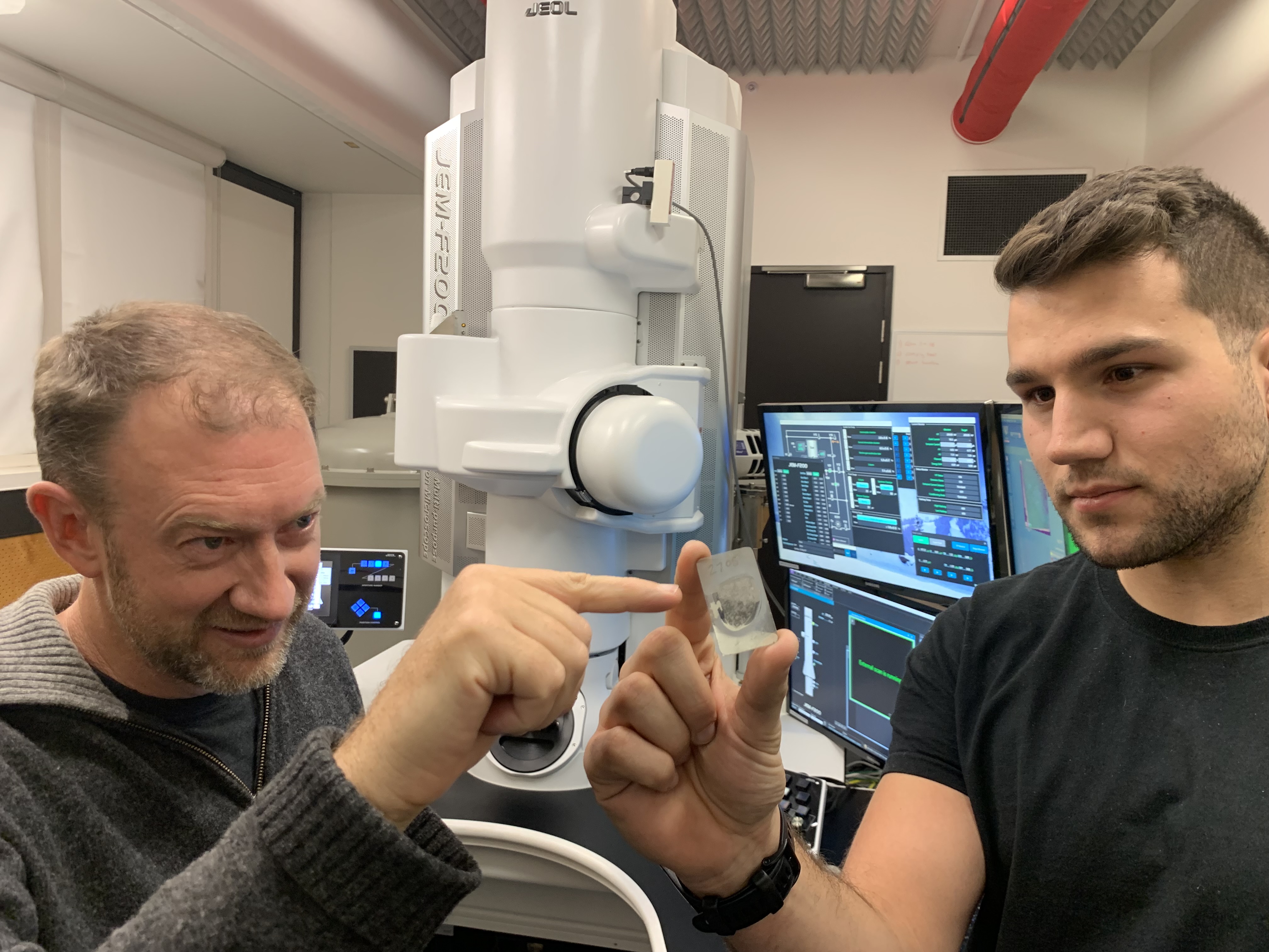 Monash University Professor Andy Tomkins (left) with RMIT University PhD scholar Alan Salek holding a ureilite meteor sample at the RMIT Microscopy and Microanalysis Facility. Credit: RMIT University