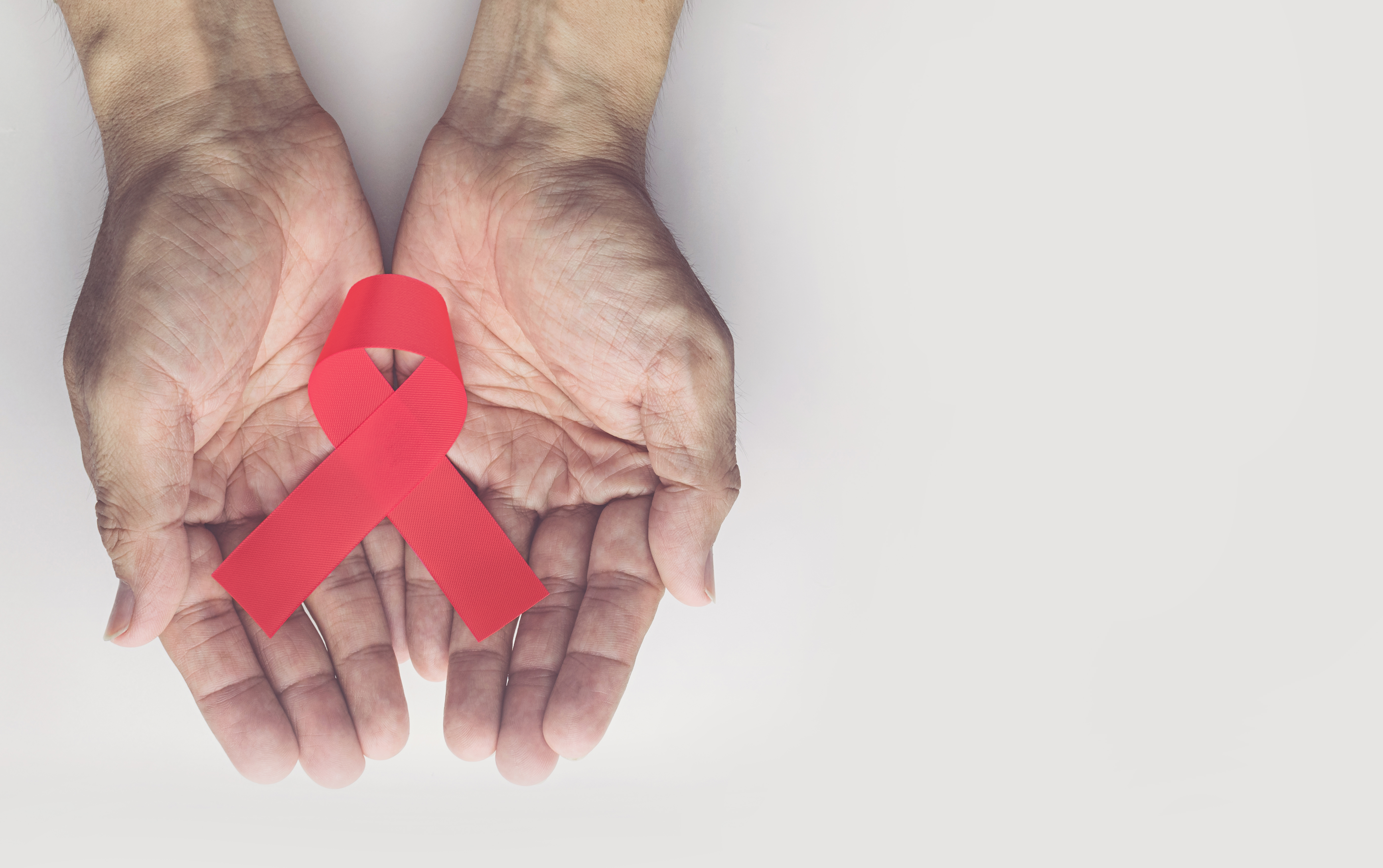 Shutterstock image of HIV ribbon, two hands 
