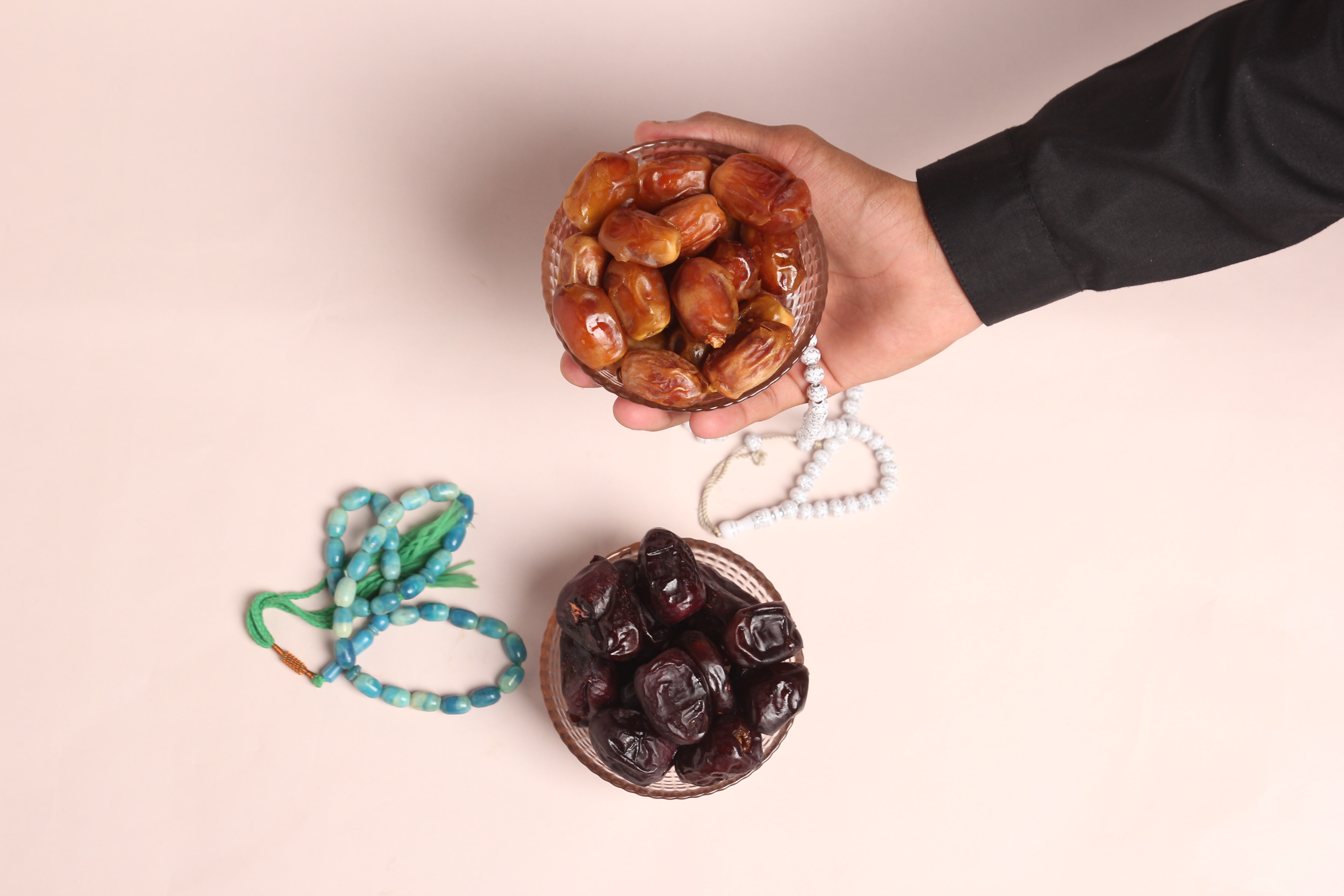 Beautiful Dates in cup with prayer Beads photography on light pink background. Photo by Rauf Alvi on Unsplash