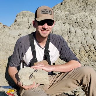 Voris doing fieldwork holding rock containing tyrannosaur tooth